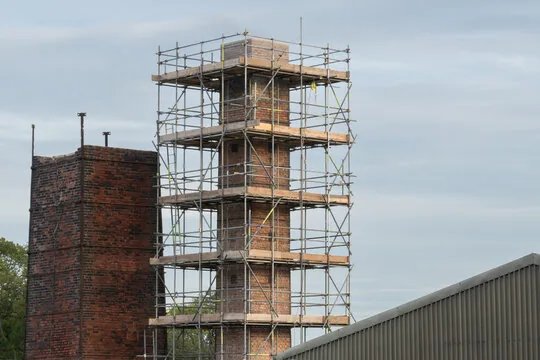Scaffold around a tall brick chimney